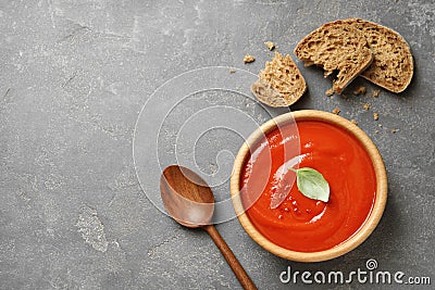 Bowl of fresh homemade tomato soup and bread on grey background, top view. Stock Photo