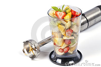 A bowl full of chopped fruit to prepare a smoothie next to the blender isolated Stock Photo