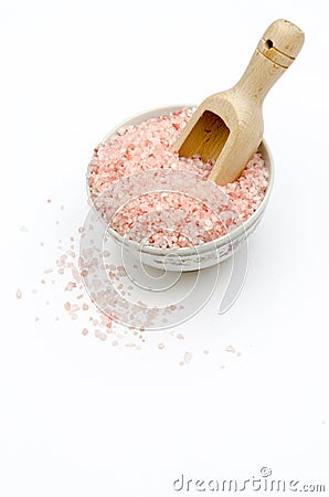 bowl full of pink bath salts, spoon, grains of salt fallen, on white background frontal view Stock Photo