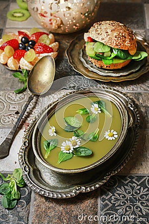 Bowl of green pea soup, fruit salad and vege burger bun with vegetables Stock Photo