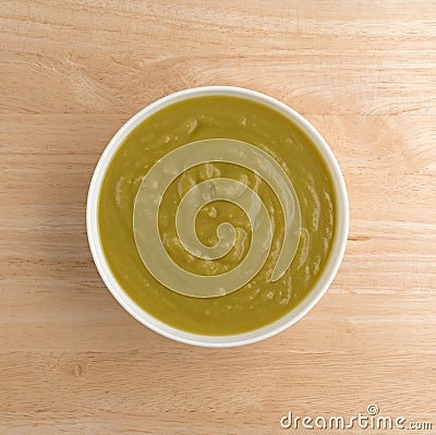 Bowl of green pea soup on a wood table top Stock Photo
