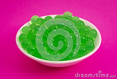 Bowl of Green Popping Boba Pearls on a Bright Pink Background Stock Photo