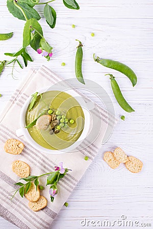 Bowl of homemade green spring pea soup topped with pumpkin seeds, croutons. On white background. Stock Photo