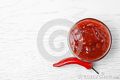 Bowl of hot chili sauce with red pepper on white wooden background. Stock Photo