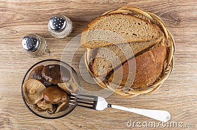 Bowl with marinated lactarius, bread in wicker basket, salt, pep Stock Photo
