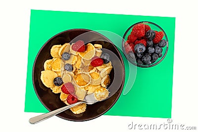 A bowl with mini pancake cereal. Tiny cereal pancakes with blueberries and raspberries Stock Photo