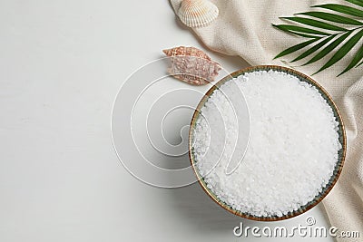 Bowl of natural sea salt, shell and leaf on white wooden table, flat lay. Space for text Stock Photo