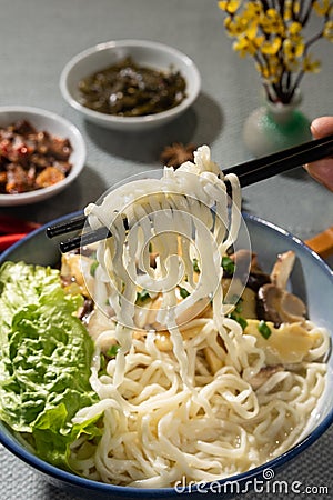 a bowl of noodles with chopsticks holding up a piece Stock Photo