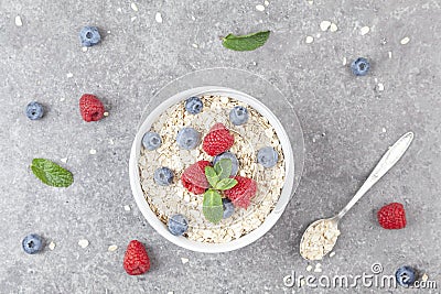 Bowl of oat granola with fresh raspberries, blueberries and mint for healthy breakfast, top view. Portion of cereal garnished Stock Photo