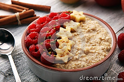 Bowl of oatmeal porridge with banana, raspberries coconut and caramel sauce on rustic table, hot and healthy food for Breakfast Stock Photo