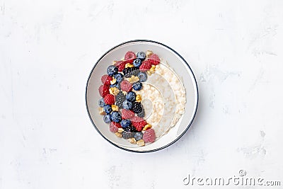 Bowl of oatmeal porridge with blueberry and raspberry on white table top view. Yummy and diet breakfast Stock Photo