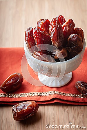 A bowl of organic medjool dates on an embroidered orange cloth. Stock Photo
