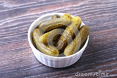Bowl with pickled gherkins, cucumbers on wooden background close up. Pickles. Stock Photo