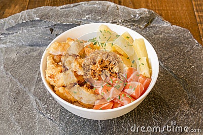 Bowl with raw salmon, pineapple chunks, tempura vegetables and fried onion Stock Photo