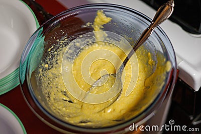 A bowl of regular cornbread batter being spooned into cupcake papers Stock Photo