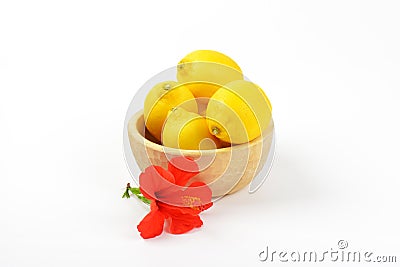 Bowl of ripe lemons and red hibiscus bloom Stock Photo