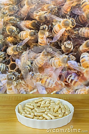 Bowl of Royal Jelly in capsules with blurred background of worker bees working in honeycomb Stock Photo