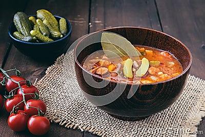 Bowl with Solyanka, a spicy and sour soup of Russian origin, on dark wooden table Stock Photo