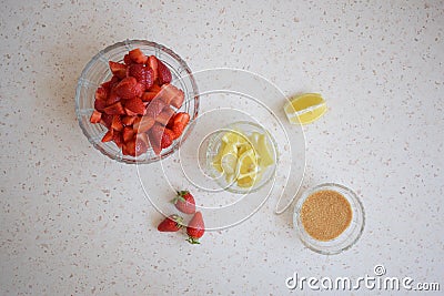 A bowl of strawberries, a lemon and brown sugar. Stock Photo