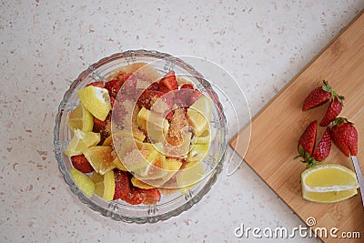 A bowl of strawberries, a lemon and brown sugar. Stock Photo