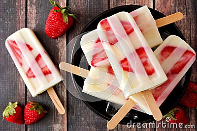 Bowl of strawberry vanilla yogurt popsicles on dark wood Stock Photo