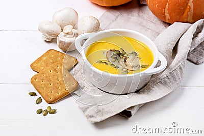 Bowl of Tasty Homemade Pumpkin Cream Soup decotated with Mushrooms and Pumpkin Seeds White Wooden Background View from Above Stock Photo