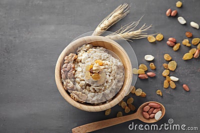 Bowl with tasty oatmeal, raisins and nuts on grey background Stock Photo