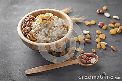 Bowl with tasty oatmeal, raisins and nuts on grey background Stock Photo