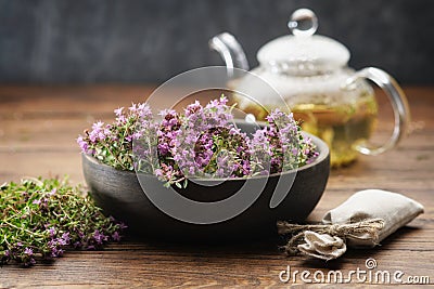 Bowl of thyme healing herbs, sachet bag full of thymus serpyllum medicinal herbs. Glass tea kettle of thyme healthy herbal tea. Stock Photo