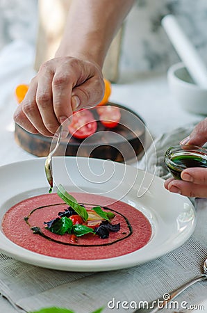 Bowl of tomato soup with basil on white background. Cold pink tomato soup. Restaurant supply. Stock Photo