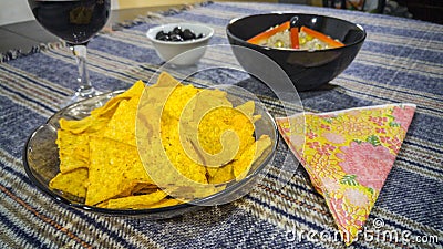 Bowl of tuna salad, tortilla chips, olives and glass of red wine Stock Photo