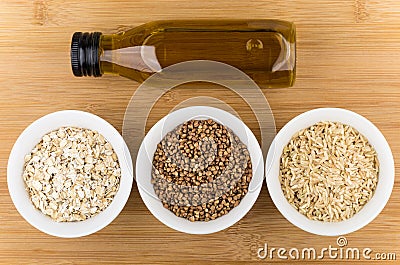 Bowls with oats, buckwheat, brown rice and bottle oil Stock Photo