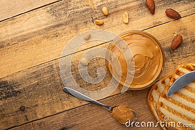 Bowls of peanut butter and peanuts on a dark wooden background from top view, rich breakfast Stock Photo