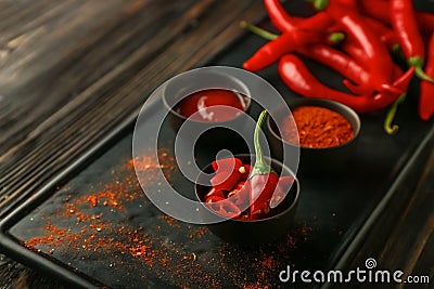 Bowls with red hot chili pepper, powder and sauce on plate, closeup Stock Photo