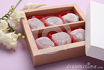 Box of delicious mochi and flowers on light background, closeup. Traditional Japanese dessert Stock Photo