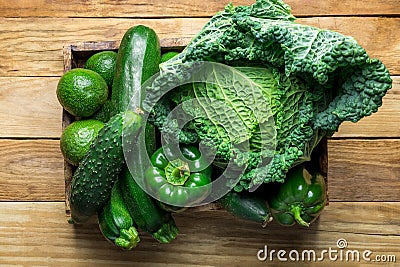 Box with Fresh Organic Green Vegetables Savoy Cabbage Zucchini Cucumbers Bell Peppers Avocados on Aged Plank Wood Background Stock Photo