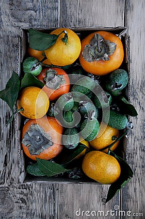 A box with a fresh persimmon, feijoa and citrus mandarins. Above Stock Photo