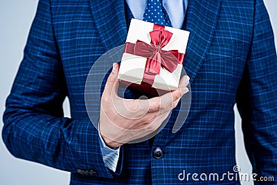 Box pack tied with elegant red ribbon being held in male hand formal style for holiday celebration, gift Stock Photo