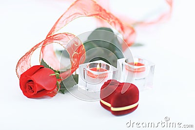 Box with ring, rose and two candles on white background Stock Photo