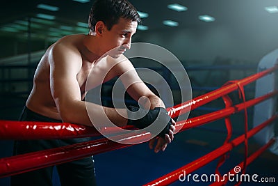 Boxer in black bandages poses on ring ropes Stock Photo