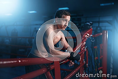 Boxer in black handwraps poses on ring ropes Stock Photo