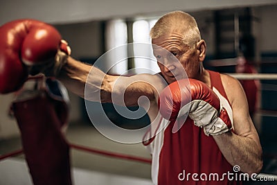 Boxer practicing her punches at a boxing studio. Close up of a male boxer punching inside a boxing ring Stock Photo