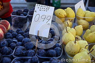 Boxes full of fresh black amber plums with dusty white waxy coating selling next to pears and peaches in local city fruit market Stock Photo