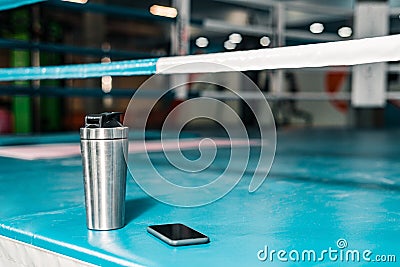 On the boxing ring there is a thermos with water and a smartphone is next to it. Stock Photo