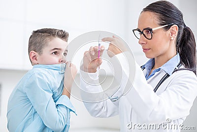 The boy is afraid of injections before preventing vaccination. Young doctor preparing a vaccine for a boy in an ambulance Stock Photo