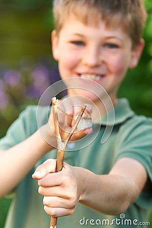 Boy Aiming Slingshot In Garden Stock Photo