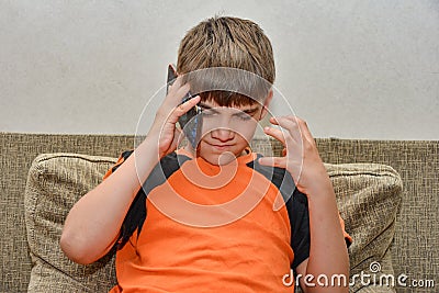 A boy with anger and discontent talks on the phone, waving his arms. The concept of dissatisfied customers and buyers Stock Photo