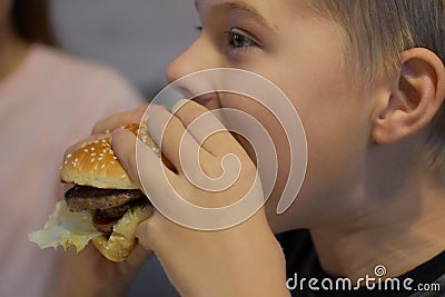 Boy with appetite eats delicious hamburger. child bites off large piece of sandwich Stock Photo