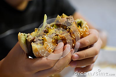 Boy with appetite eats delicious hamburger. child bites off large piece of sandwich Stock Photo