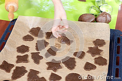 Boy arranges cut out cookie shapes on a baking tray. In the background, silicone coffee table and cookie cutters. Stock Photo